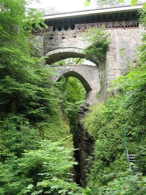 an old stone bridge over a small stream in the middle of a lush green ...