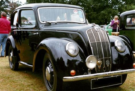 an old black car parked on top of a grass covered field