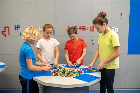 Crianças brincando com lego em pé ao redor da mesa | Foto Premium