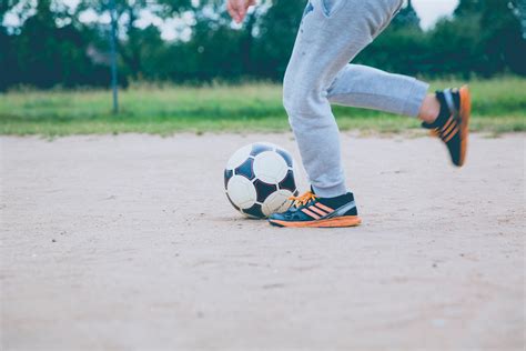 Soccer Player Kicking White Gray Soccer Ball on Green Grass Field · Free Stock Photo