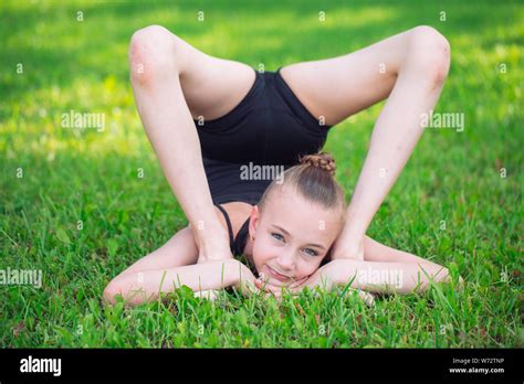 Beautiful little girl doing gymnastics on the grass on a sunny day ...