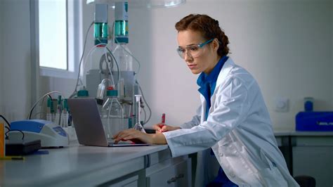 Scientist find a cure. Woman scientist looking at chemical liquid in lab flask. Female scientist ...