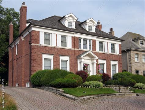 Large brick two storey home with white shutters Stock Photo | Adobe Stock