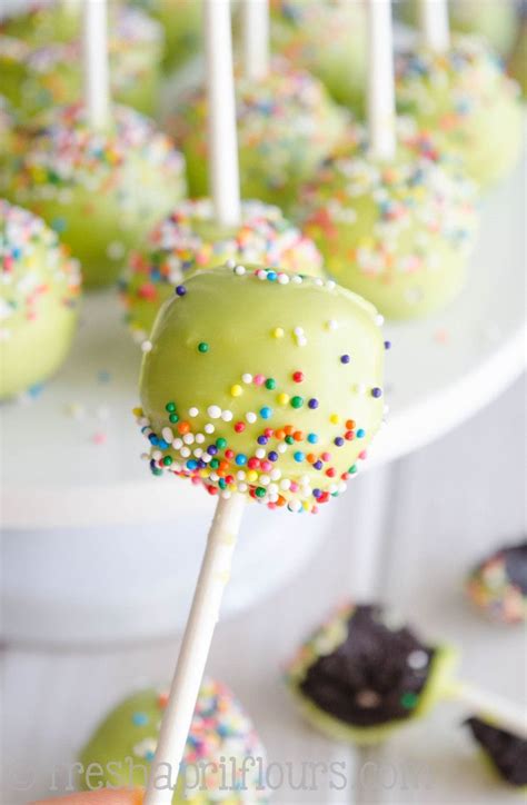 green cake pops with sprinkles are on a white platter and ready to be eaten