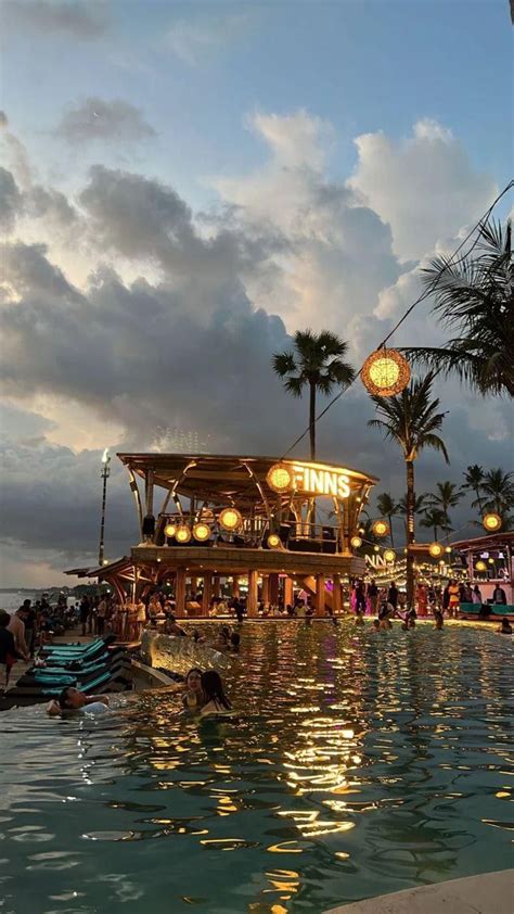 people are swimming in the pool at dusk with palm trees and lights ...