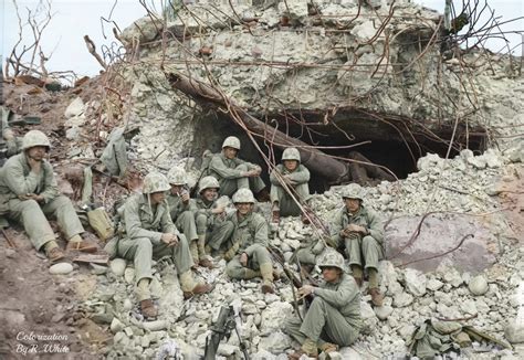 Battle hardened United States Marines rest for a moment in front of a blown out Japanese coastal ...