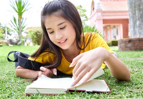 Premium Photo | Girl reading book while lying on grass in public park