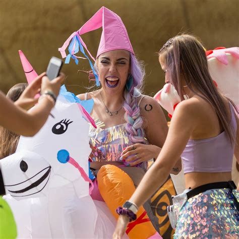 Women with colorful hair laugh and ride on inflatable unicorns at the ...