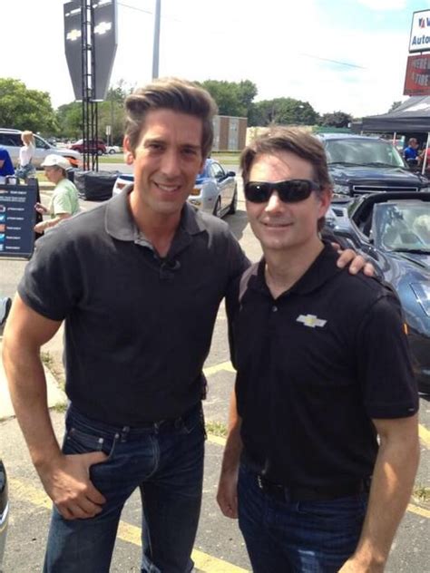 two men standing next to each other in front of parked cars