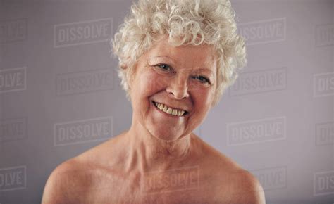 Headshot of a beautiful mature woman isolated on grey background. Shirtless caucasian old female ...