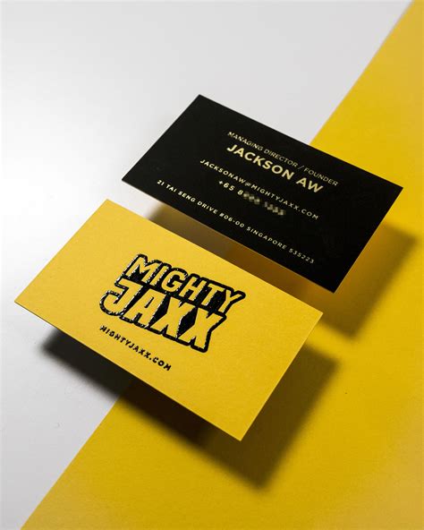 two business cards sitting on top of each other next to a yellow and ...