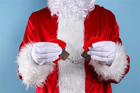 Premium Photo | Handcuffs in santa claus hands on blue background