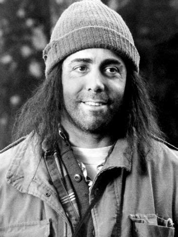 a black and white photo of a man with long hair wearing a knitted hat