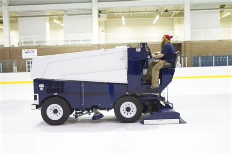 a man sitting in the back of a truck on top of an ice covered rink