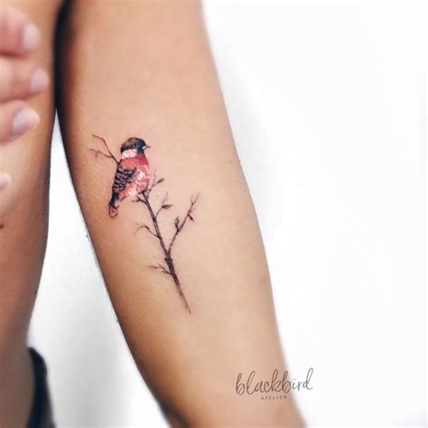 Bird on a branch tattoo on the left inner arm.