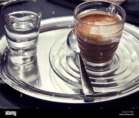 Espresso macchiato on metall tray and glass with water Stock Photo - Alamy