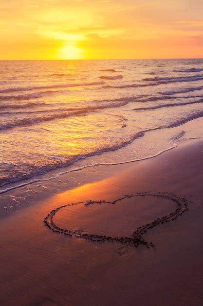 Premium Photo | Heart shape drawn on a sandy beach at sunset