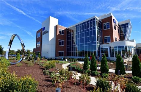 an office building with many plants and trees in the foreground, on a sunny day