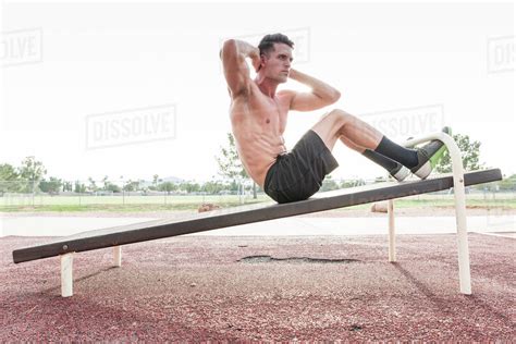 Caucasian man doing sit-ups outdoors - Stock Photo - Dissolve