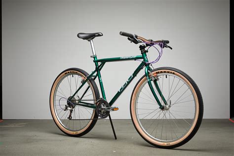 a green bike with brown rims parked in a garage area next to a white wall