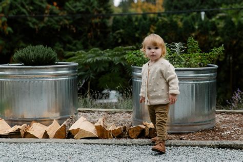 Little girl standing in garden near firewood · Free Stock Photo