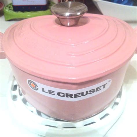 a pink crock pot sitting on top of a stove