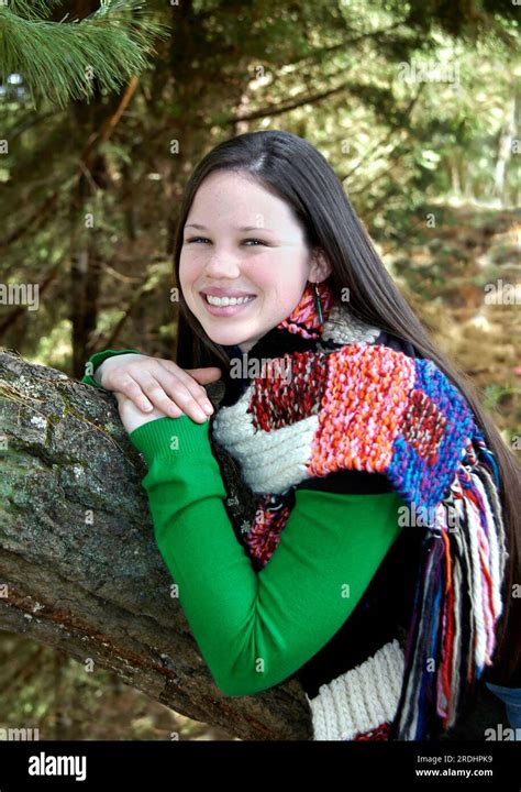 Glowing with happiness, this teenager poses leaning against a tree trunk. She is visiting ...