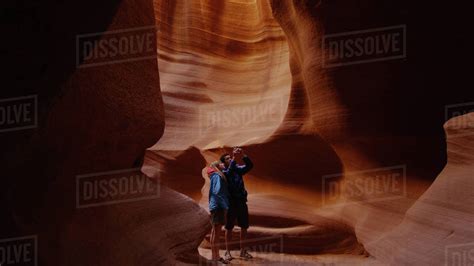 Hiking couple photographing majestic grooved rock formation caves - Stock Photo - Dissolve