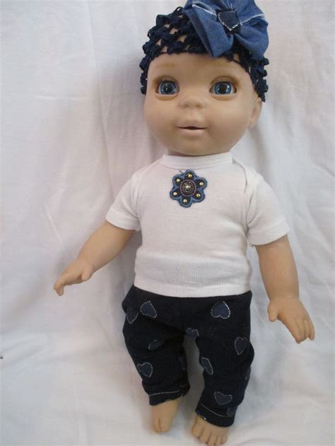 a doll with blue eyes wearing a white shirt and black pants on a white background