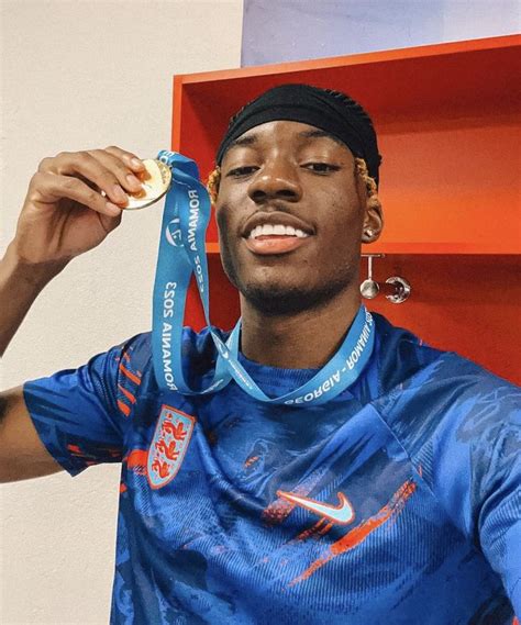 a man holding up a medal in front of his face and wearing a blue shirt