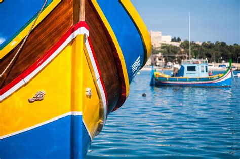 several boats are docked in the water near each other and one is yellow, red, blue, and green