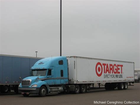 a large blue semi truck parked in front of a building with a flag on top