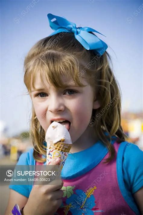 Young girl eating ice cream cone - SuperStock