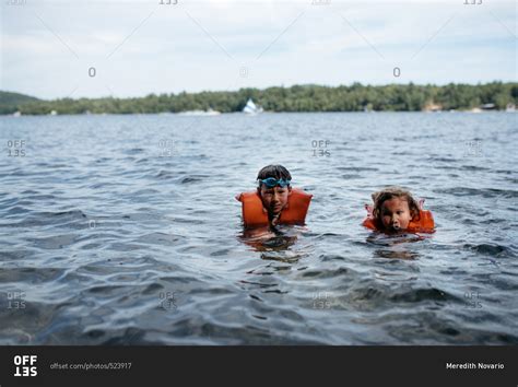 Two young children swimming in a lake stock photo - OFFSET