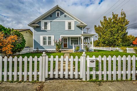 Royalty-Free photo: White and blue wooden house with open field under white skies at daytime ...