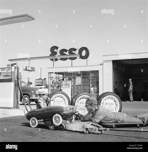 Service station of the 1950s. A boy in his pedal car has it serviced at an Esso petrol station ...