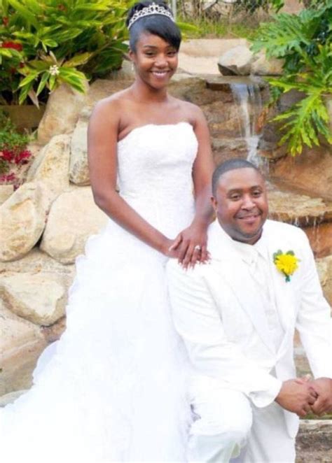 a bride and groom pose for a photo in front of a waterfall at their wedding