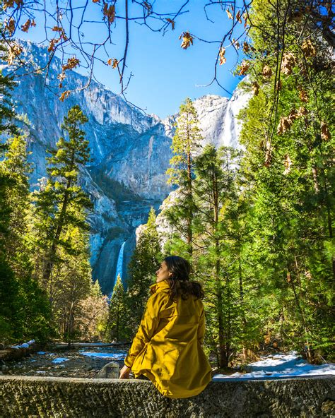 woman in yellow jacket with view of yosemite falls - Le Wild Explorer