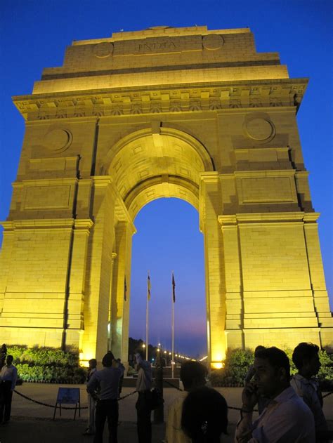 people are standing in front of an arch at night