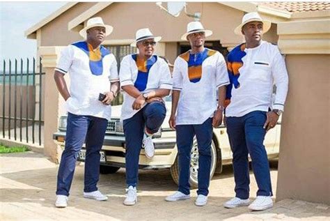 four men in white shirts and blue jeans standing next to a car