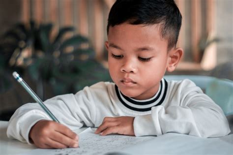 Premium Photo | Child boy holding pencil writing. Asian Boy doing homework, kid writing paper ...