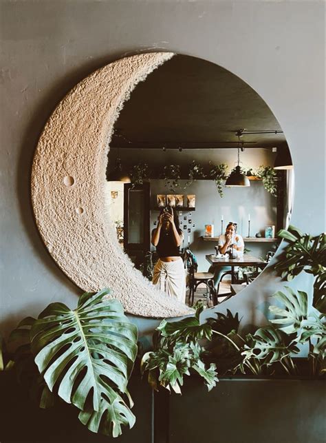 a woman taking a photo of herself in front of a mirror with the moon on it