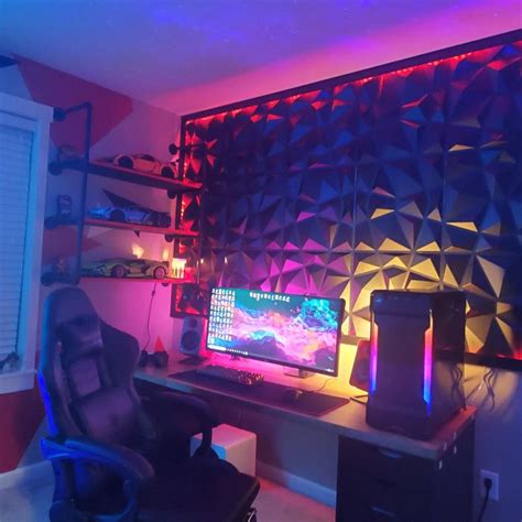 a room with a desk, chair and computer monitor on it's side in front of a colorful wall