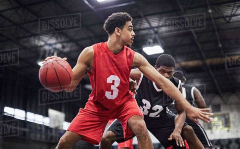 Young male basketball player dribbling the ball, playing game in gymnasium - Stock Photo - Dissolve