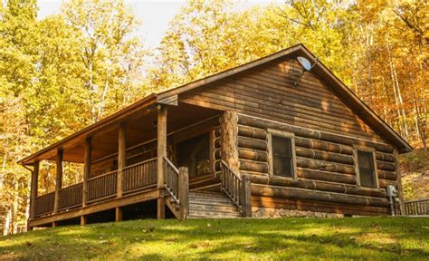 a log cabin in the woods with stairs leading up to it's second floor