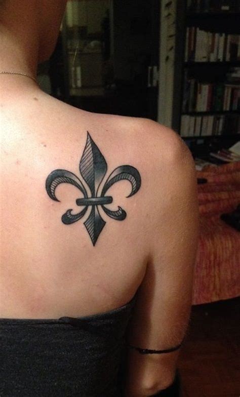 a woman with a black and grey fleur de lis tattoo on her back