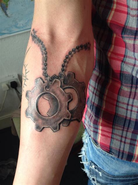 a person with a tattoo on their arm holding a chain and a wrench in the shape of a cogwheel