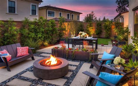 an outdoor fire pit surrounded by chairs and tables in a backyard area with seating around it