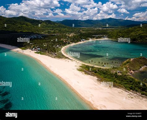 Aerial drone view of an empty, beautiful tropical beach surrounded by coral reef and greenery ...