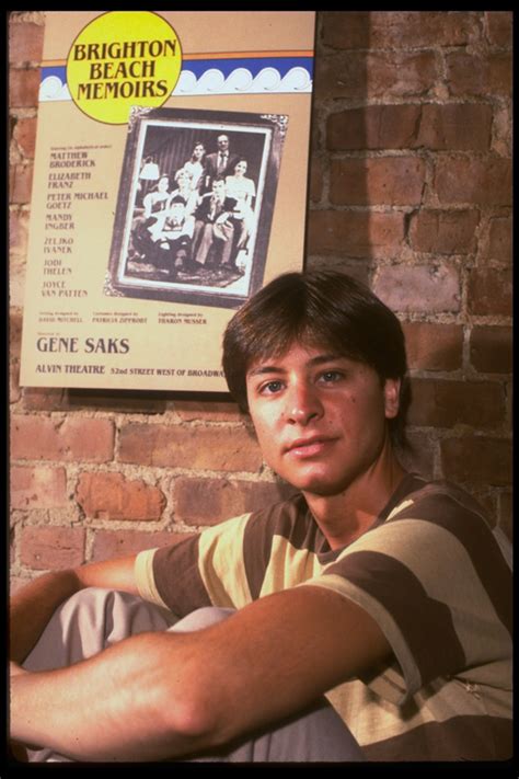 Publicity photo of actor Fisher Stevens sitting in front of poster for Broadway play "Brighton ...